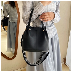 Detail of black lychee grain leather bucket bag with geometric embroidered wide strap