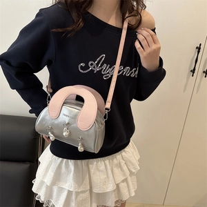 Silver mini shell bag with pink U-shaped handle and pearl charms worn by model