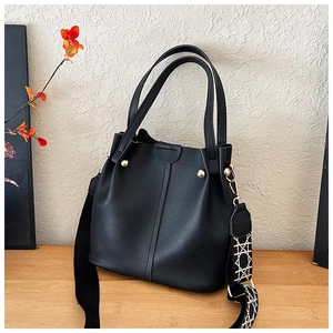 Close-up of black lychee grain bucket bag with geometric wave pattern wide strap