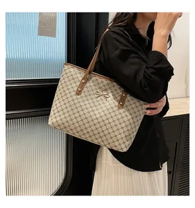 Détail du grand sac cabas avec motif monogramme vintage et fermoir noeud doré à l'épaule