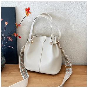 Detail of off-white bucket bag with lychee texture and ethnic style fabric strap