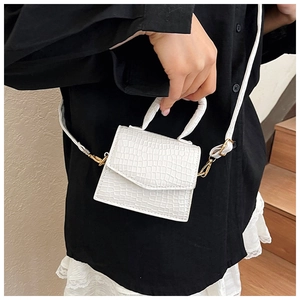 Dettaglio mini borsa bianca con trama a coccodrillo, finiture dorate e manico rotondo