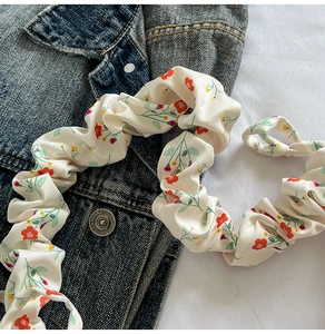 Close-up of vintage floral fabric scrunchie with orange blooms and textured pleats