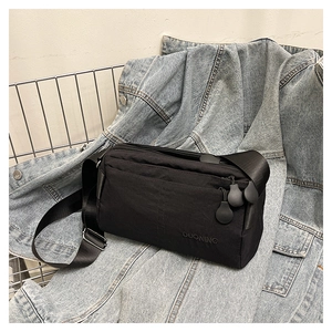 Detail of minimalist nylon crossbody bag with zipper pockets on blue denim jacket