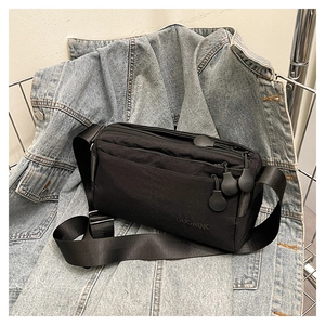 Close-up of black nylon crossbody bag with multi-zipper layers and embossed logo