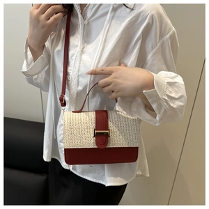 Detail of straw patchwork handbag with red leather trim and gold metal buckle hardware