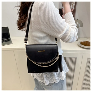 Detail view of black PU leather shoulder bag with golden double chain and small side pouch