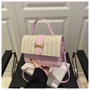 Close-up of pink leather handbag with woven straw flap and gold metal buckle detail