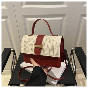 Detail of red leather contrast stitching and woven straw texture on fashion handbag
