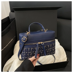 Detail view of navy blue box bag with tweed texture and double tassel zippers