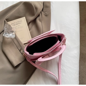 Pink PU leather handbag with bow detail showing interior zip pocket and adjustable strap