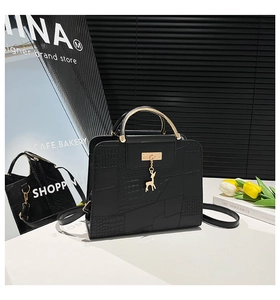 Detail of luxury black crocodile texture bag with golden deer charm and metal handle