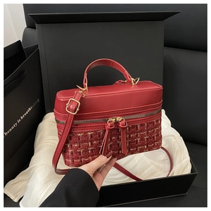 Detail of red tweed and leather box bag featuring gold zippers and silk background