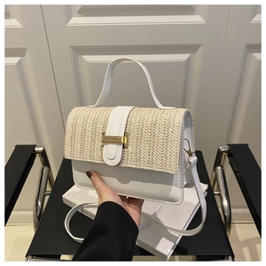 Detail of color-block handbag showing woven straw flap and white faux leather finish