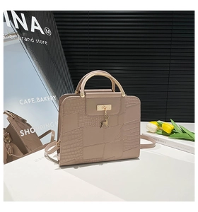 Detail of beige faux crocodile leather handbag with gold handle and deer charm