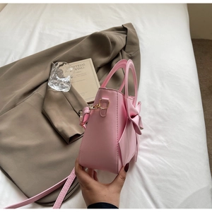 Detailed side view of pink bow handbag on white bed linen with soft natural lighting