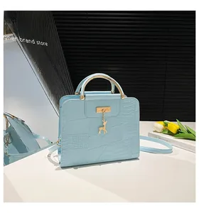 Detail of light blue crocodile embossed handbag with gold metal handle and deer charm