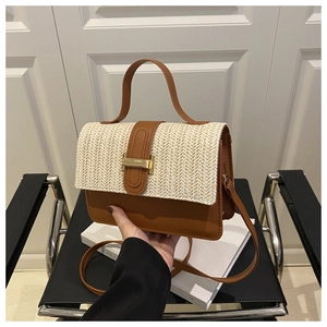 Detail of straw and brown leather shoulder bag featuring a gold metal T-lock and handle