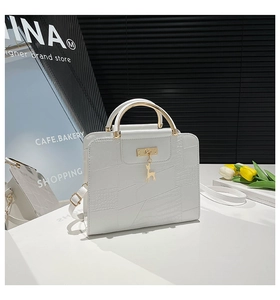 Detail of white crocodile embossed leather bag with gold handle and deer charm