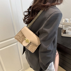 Elegant beige floral embossed crossbody chain bag shown on a grey blazer outfit