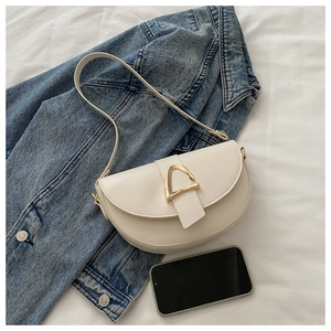 Detail of cream white leather saddle bag with gold D-buckle on blue denim jacket