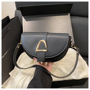 Detail of a black leather saddle bag with gold D-buckle in a premium gift box setup