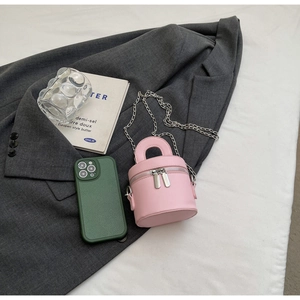 Detailed top view of pink cylinder bag with dual silver zippers on grey blazer