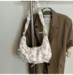 Detail of floral hobo bag with red flower patterns and ruffled strap on a brown blazer