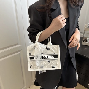 White jacquard tote bag with black rose pattern and fashion ribbon on model