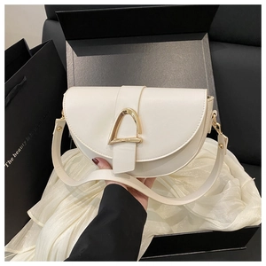 Detailed close-up of a white saddle bag with a gold metal buckle in a luxury gift box