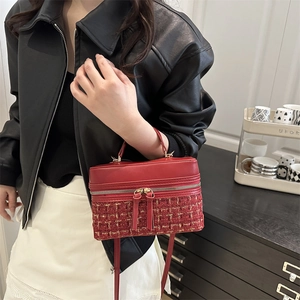 Red box-shaped handbag with tweed patchwork and tassel detail held by model