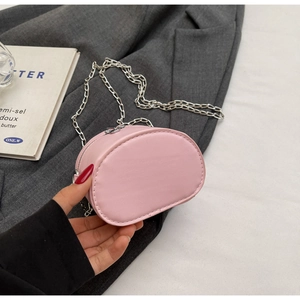 Detail view of a pink mini crossbody bag with a silver chain held in hand