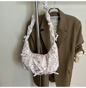 Detail of floral crescent bag with ruched shoulder strap and cute bow tie decoration