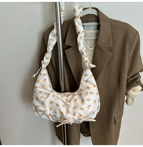 Detail of white floral satin shoulder bag with pleated straps and bow decorations
