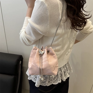 Pink drawstring bucket bag with silver butterfly clasp and pearl charms on model
