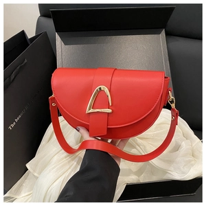Detail of red crescent saddle bag with gold hardware buckle and leather shoulder strap