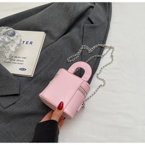 Pink cylindrical mini box bag featuring a silver chain strap and top handle held by hand