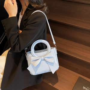 Elegant light blue handbag with a large bow detail and round handle for women