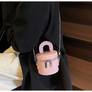 Detailed close-up of a pink mini bucket bag with dual silver zippers and chain strap