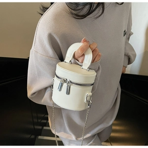 Detailed macro view of white cylinder leather bag with silver double zippers and handle
