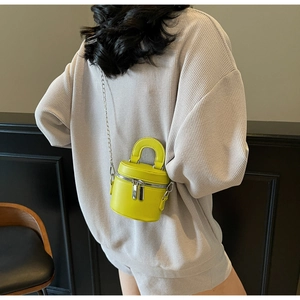 Detail view of lime green mini bucket bag with dual zippers and silver chain strap