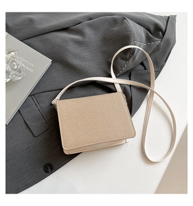 Dettaglio della borsa a tracolla beige con trama diagonale su un blazer grigio