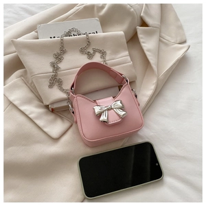 Mini sac rose en cuir avec nœud argenté et chaîne à côté d'un téléphone pour la taille