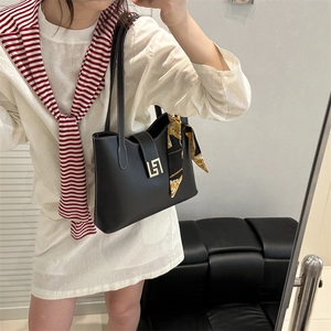 Classic black leather shoulder bag with gold buckle and silk scarf on a model
