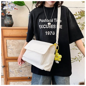Close-up of white nylon tote bag with flip cover and yellow flower plush keychain