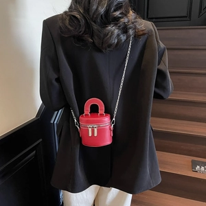 Fashionable red leather bucket bag with dual zippers worn on a black blazer