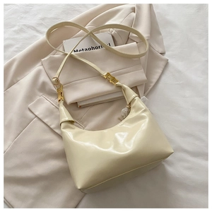Close-up of beige moon bag with smooth PU leather texture and gold metal buckle detail