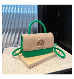 Détail du sac en cuir vert avec rabat tressé beige et logo métallique doré lettre M