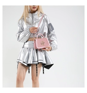 Detail of pink woven crossbody bag styled with metallic silver fashion apparel