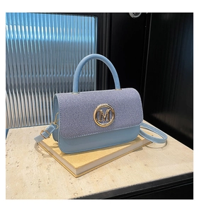 Détail du sac à bandoulière en cuir bleu clair avec rabat rayé et logo M doré chic